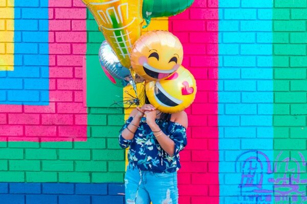 woman covering face with assorted ballons